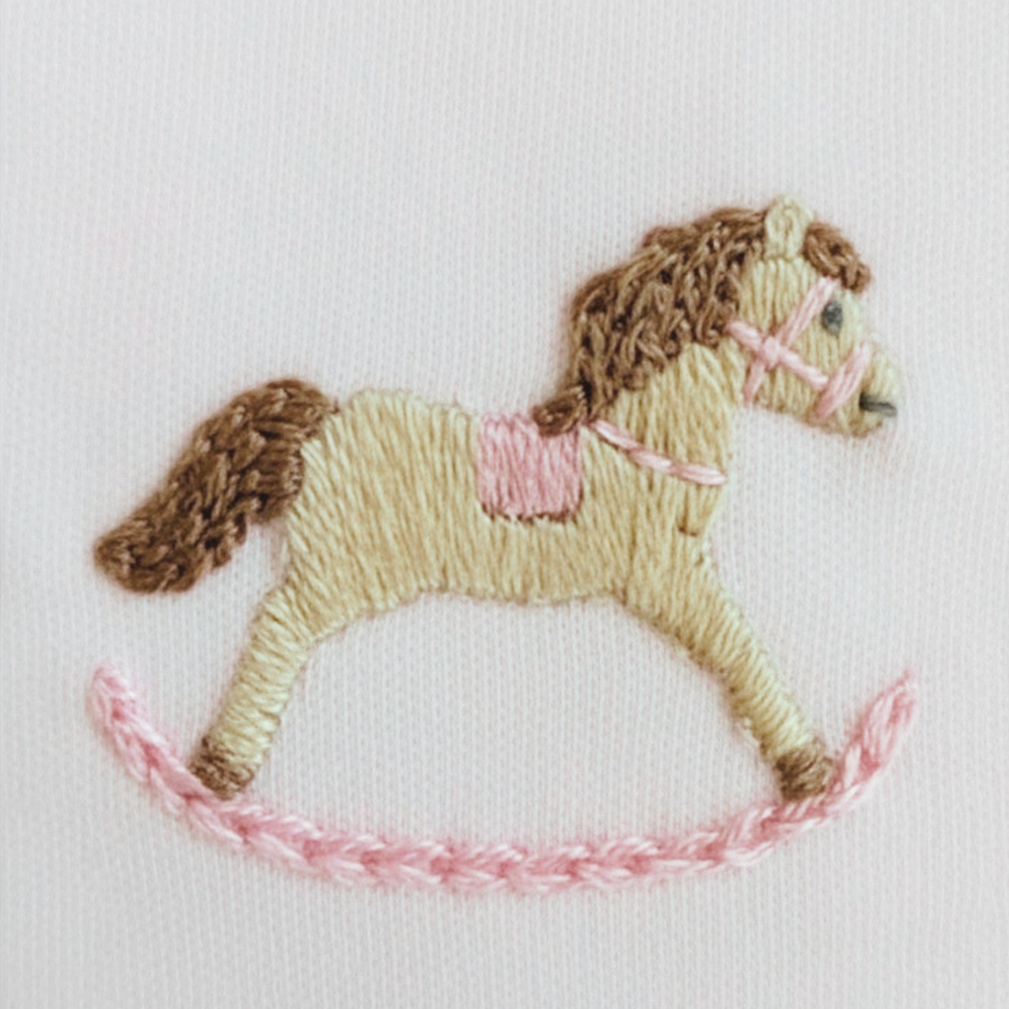 Embroidered horse design on a white fabric background