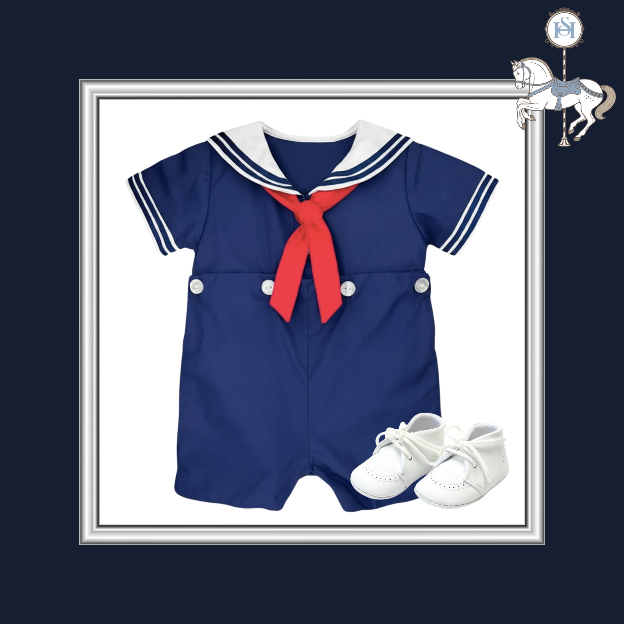 A baby short-sleeve romper in navy blue with a white sailor collar, white trim, and a red neck bow, shown with a pair of white baby shoes on a white background inside a silver frame. A small carousel horse graphic appears in the top right corner.