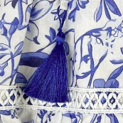 Blue tassel on a white fabric background with blue floral patterns